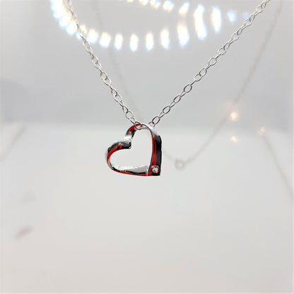 Sterling silver ribbon style heart with a tiny zircona at the base is suspended from a sterling silver chain a