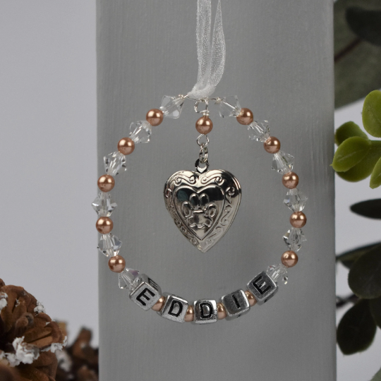 pet memorial keepsake with locket. crystals and pearls surround your pet's name. In the centre of the circle is a silver colour locket with a paw print on the front. The locket opens for you to add a photo of your beloved pet.