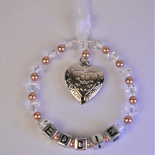 pet memorial keepsake with locket. crystals and pearls surround your pet's name. In the centre of the circle is a silver colour locket with a paw print on the front. The locket opens for you to add a photo of your beloved pet.