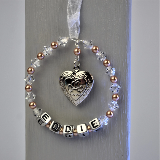 pet memorial keepsake with locket. crystals and pearls surround your pet's name. In the centre of the circle is a silver colour locket with a paw print on the front. The locket opens for you to add a photo of your beloved pet.