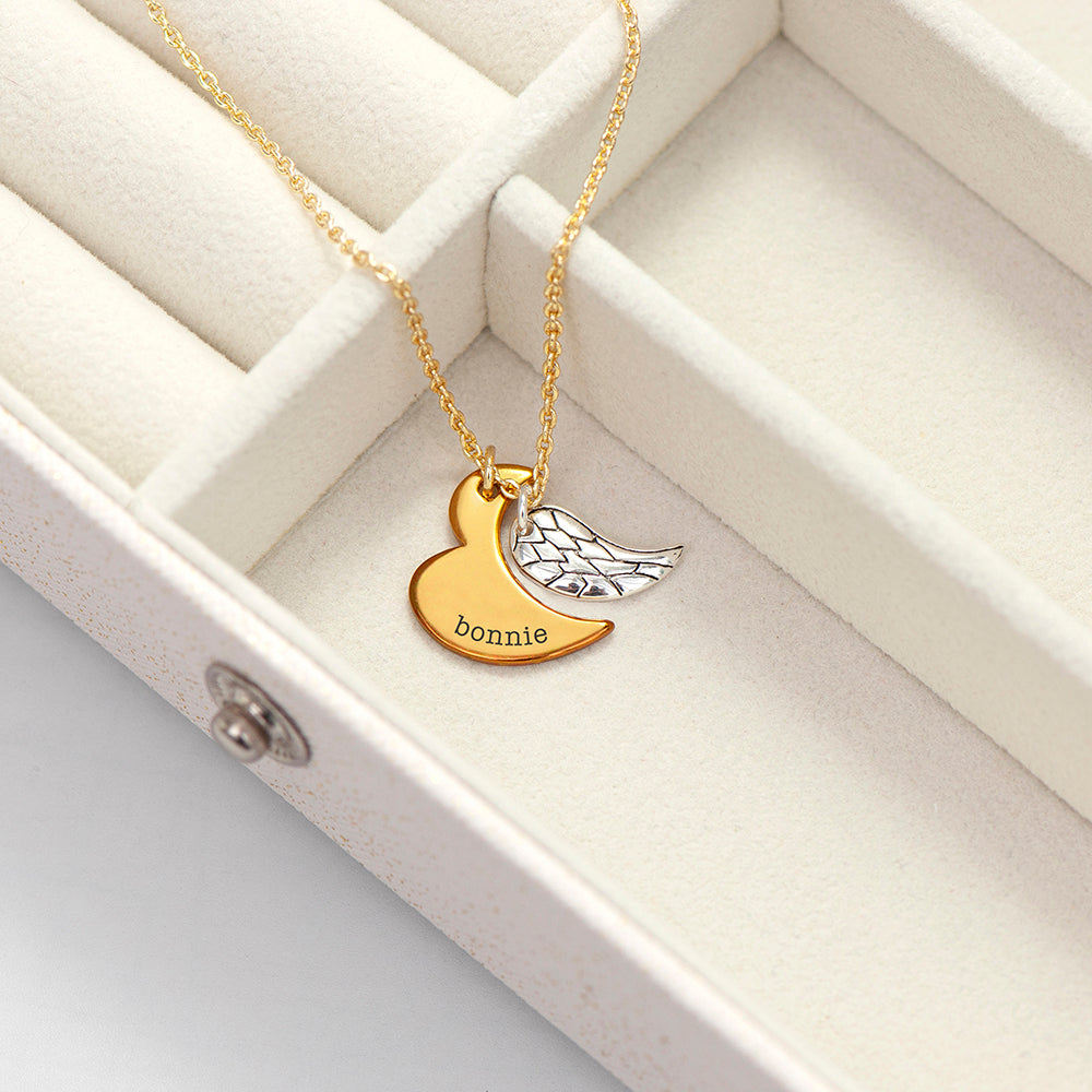 Silver plated angel wing charm is hung next to a partially formed gold plated heart. Together they complete the heart shape. gold part of heart can be engraved with a name of your choice.