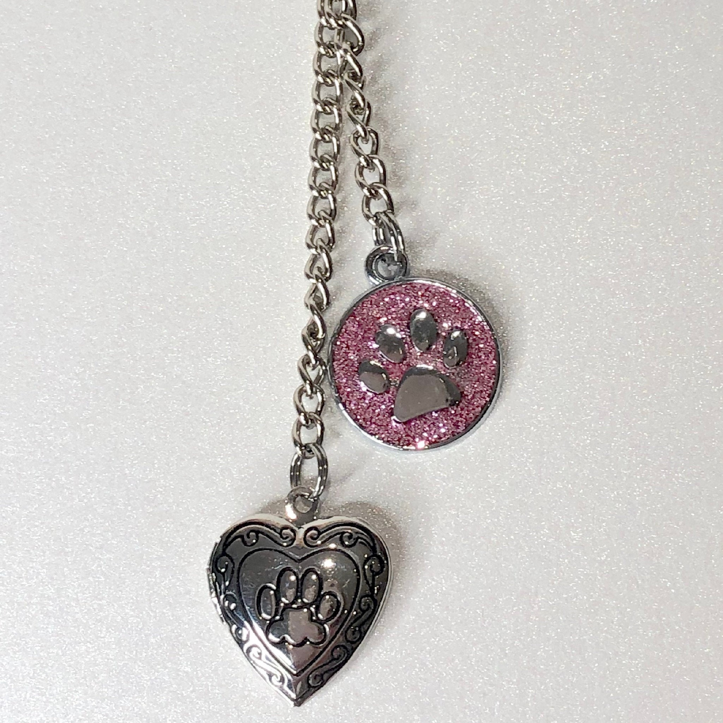 Heart shaped locket with paw print is teamed with a pink glitter charm, also with a paw print, part of the pet memorial keyring