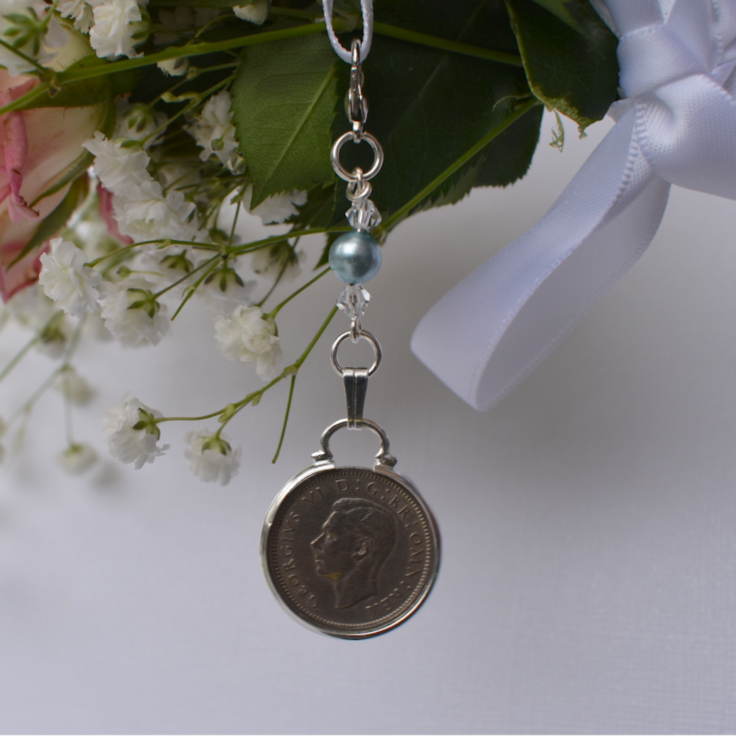 a real sixpence is securely mounted below a line of crystals with a blue bead. Finished with a lobster clasp and ribbon for you to add to your wedding bouquet