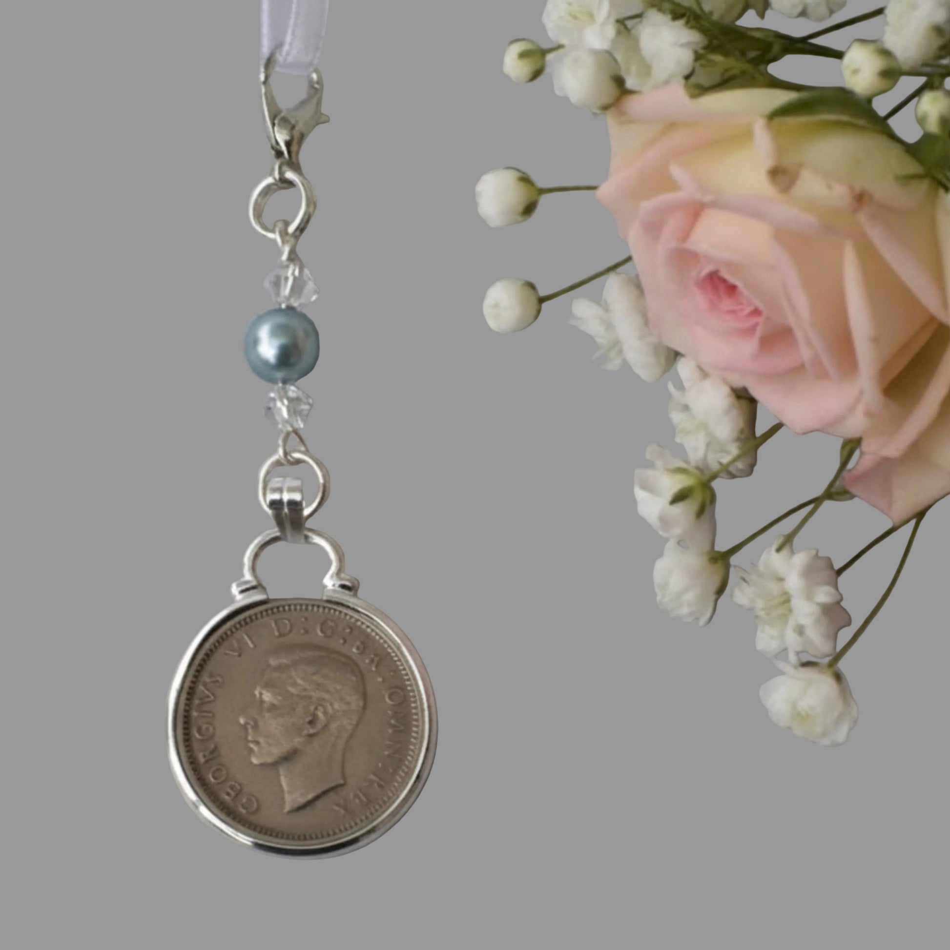 a real sixpence is securely mounted below a line of crystals with a blue bead. Finished with a lobster clasp and ribbon for you to add to your wedding bouquet