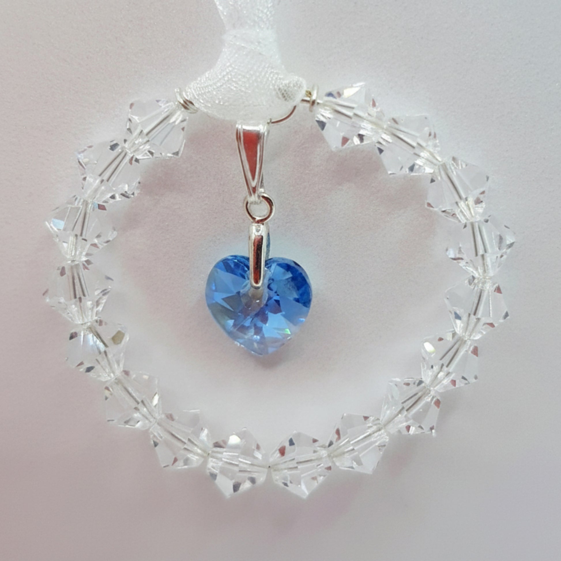 Ring of clear crystal circles surround a blue crystal heart, wedding bouquet charm