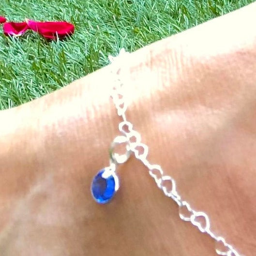 anklet with heart shaped links and blue stone being worn