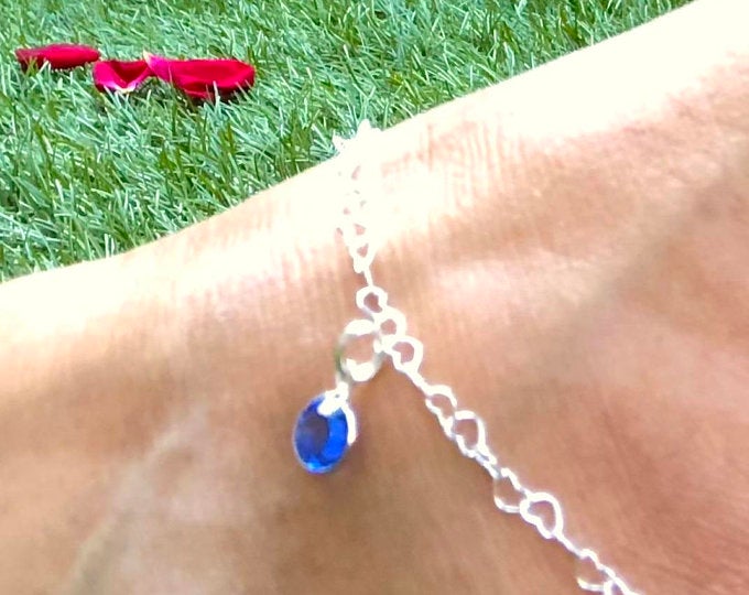 anklet with heart shaped links and blue stone being worn